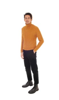 A young man standing in the studio in black jeans and gold colored.sweater with one hand in his pocket, isolated for white background.