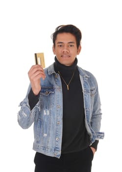 A happy young man in a jeans jacket smiling and showing his new.credit card, isolated for white background.