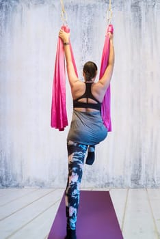 Young woman making antigravity yoga exercises in hammock
