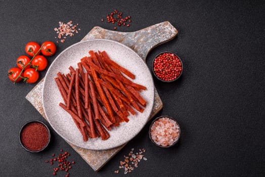 Jerky dried fish sticks with salt and spices on a dark concrete background