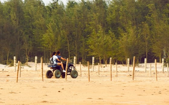 Honeymoon couple riding Motorized tricycle (three wheeled Trike motorcycle) in the coastal road of sand sea beach in summer sunset. Travel Tourism Holiday vacation background concept.
