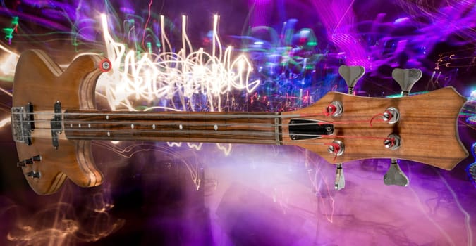 Brown bass guitar with dark fingerboard against a colorful blurred background