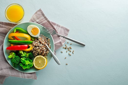 Healthy salad meal with quinoa, egg and mixed fresh vegetables on blue background top view. Food and health. Healthy meal concept