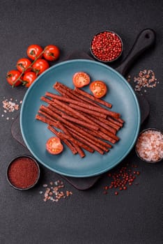 Jerky dried fish sticks with salt and spices on a dark concrete background