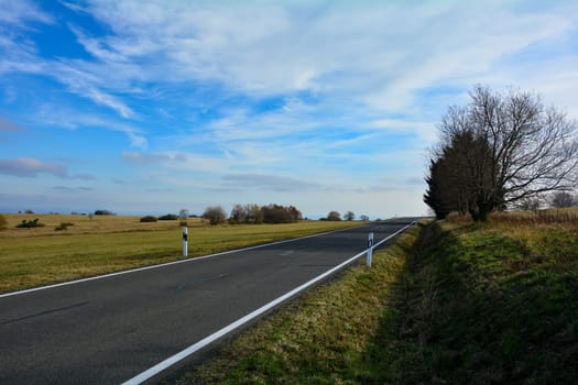Lonely road through a green landscape, with blue sky in the Rhoen, Bavaria, Germany