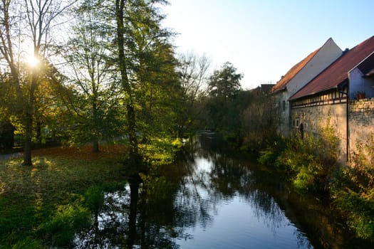 Creek with nature and old houses in the evening light,with sun n Ostheim , Rhoen, Bavaria, Germany