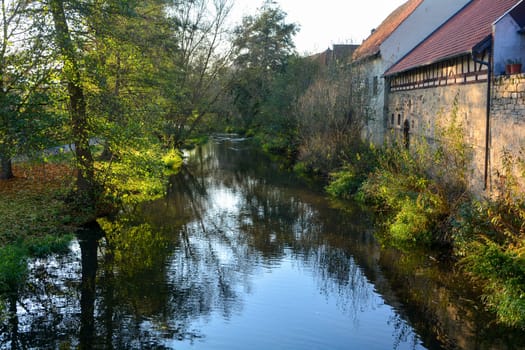 Creek with nature and old houses in the evening light,with reflection  n Ostheim , Rhoen, Bavaria, Germany