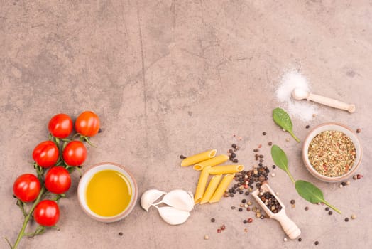 Food ingredients, italien pasta with spices like peepper corns, garlic, salt and olive oil on a brown textured stone background, empty space for text