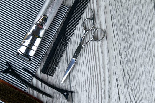 A haircut machine with scissors on a beautiful striped towel that stands on a gray wooden table. hairdresser concept with clear space