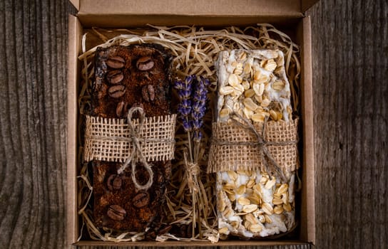 Handmade scrub soap in a cardboard box, decorated with straws, burlap and dry lavender