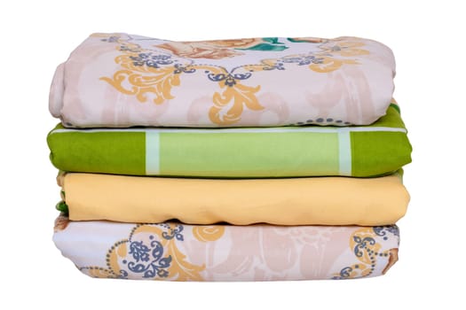 Bed linen isolated. Close-up of a stack or pile of colorful folded bed linen or duvet covers isolated on a white background. Macro of washed and ironed fabric, useful for laundry service or textile retail.