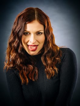 Beautiful redhead woman looking at camera and sticking out her tongue.