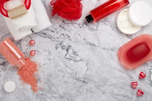 Spa still life with  toiletry, cream,  towel, masager, hearts  and flowers on light  gray marble background. Top view with copy space. Healthy lifestyle, body care, Spa treatment. Valentine