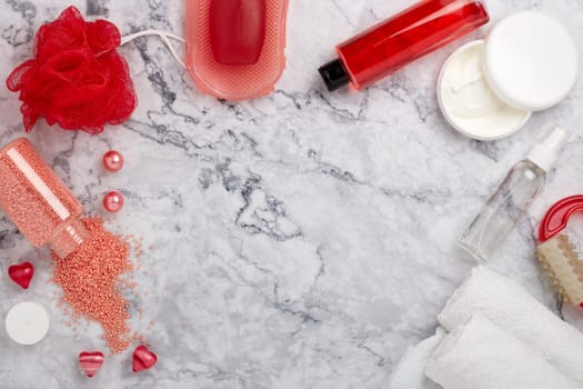 Spa still life with  toiletry, cream,  towel, masager, hearts  and flowers on light  gray marble background. Top view with copy space. Healthy lifestyle, body care, Spa treatment. Valentine