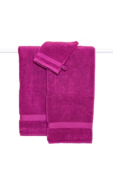 Hanging towels isolated. Closeup of violet soft terry bath towels hang on a clothes rail isolated on a white background.