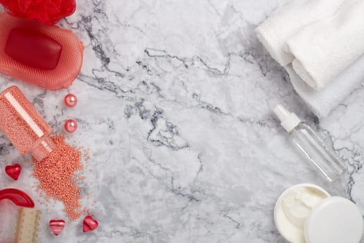 Spa still life with  toiletry, cream,  towel, masager, hearts  and flowers on light  gray marble background. Top view with copy space. Healthy lifestyle, body care, Spa treatment. Valentine