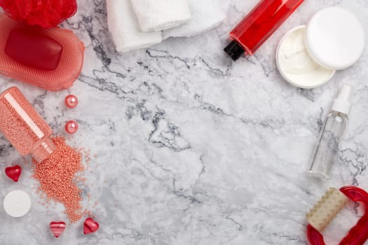 Spa still life with  toiletry, cream,  towel, masager, hearts  and flowers on light  gray marble background. Top view with copy space. Healthy lifestyle, body care, Spa treatment. Valentine