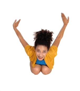 A beautiful multi-racial woman in shorts and sweater kneeling on the .floor, stretching her arms up and looking up, isolated for white.background.