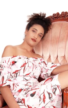 A gorgeous multi-racial woman sitting in a summer dress in an old.armchair dreaming, with her curly black hair, isolated.for white background.