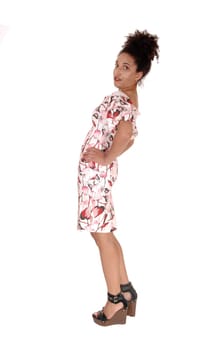 A full body image of a multi-racial woman standing in profile in summer.dress with her hands on her hip, with a slim figure and curly black.hair, isolated for white background.