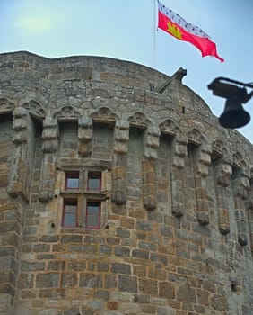 Big central stone tower with flag on top at Dinan fortress, France