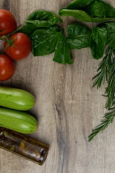 A dark bread sandwich ut in half with chicken, tomatoes, spinach, cheese and carrots stands on a wooden board that stands on a checkered white green towel. Top views