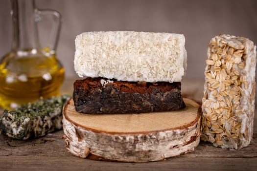 Handmade scrub soap on a wooden stand with dry mint, coconut, coffee and oatmeal
