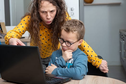 Mother and son using laptop in a kitchen at home