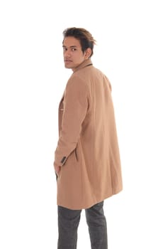 A tall young man standing in a beige coat from the back in the studio.looking over his shoulder, isolated for white background.
