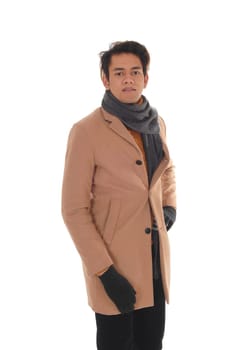 A handsome young man standing in the studio in a beige winter coat.and big scarf, looking into camera, isolated for white background.