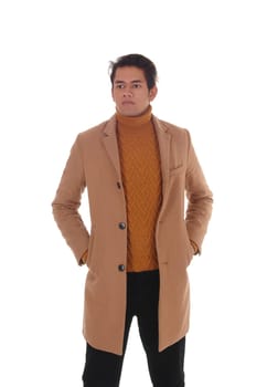 Handsome young man standing in a beige winter coat with his hands.in his pocket, wearing a sweater, isolated for white background.