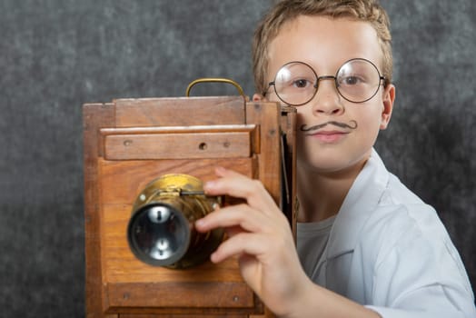 cheerful boy retro photographer with a vintage wooden camera