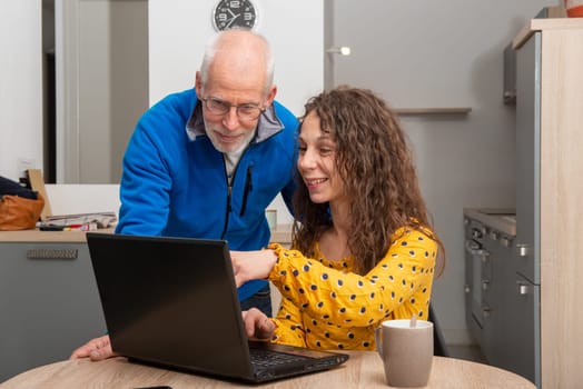 Young woman helps senior on a laptop computer