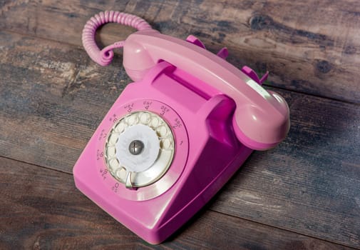 Retro pink rotary telephone on the wood table