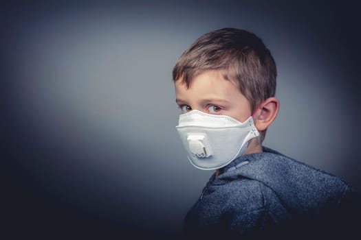 young 6 year old caucasian boy wears a protective medical mask to defend himself against the new asian crown virus. First floor, horizontal format. health and prevention concept.