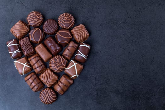 Stack of Chocolate candy in the shape of heart on a black background.  Focus on chocolate.