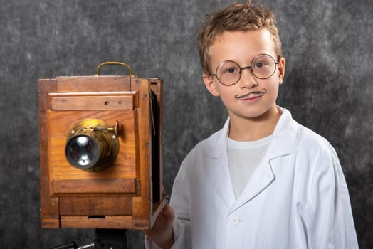 cheerful boy retro photographer with a vintage wooden camera