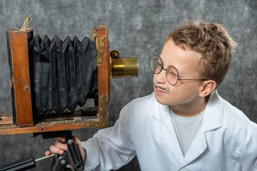 cheerful boy retro photographer with a vintage wooden camera