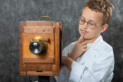 cheerful boy retro photographer with a vintage wooden camera