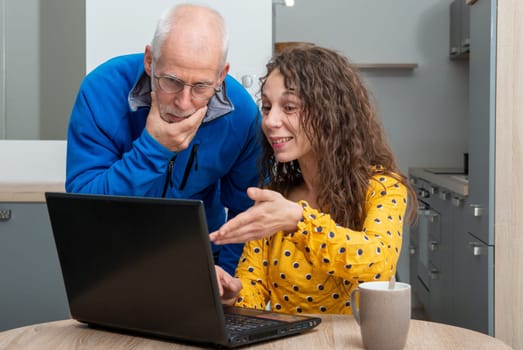 Young woman helps senior on a laptop computer