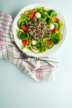 Healthy Green salad meal with fresh vegetables and quinoa seeds on blue table background