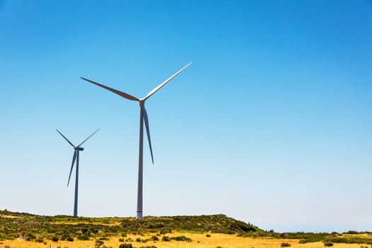 Giant windmills in the green valley against clear sky