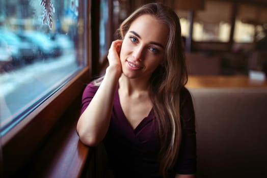 Woman waiting in cafe. Young girl sitting against the window and waiting for the order in restaurant.