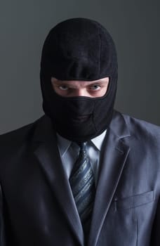 Thief in black mask and in office suit over grey