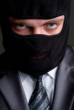 Business crime. Businessman in black balaclava looking to you