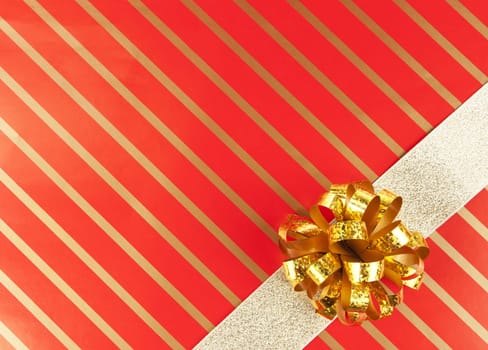 Gold ribbon and bow on striped red gift paper