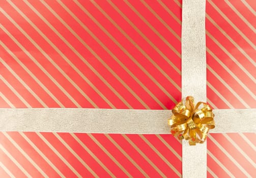 Gold ribbon and bow on striped red gift paper