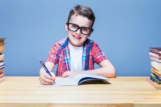 Young schoolboy learns homework, education concept. Pupil in glasses doing exercise in notebook