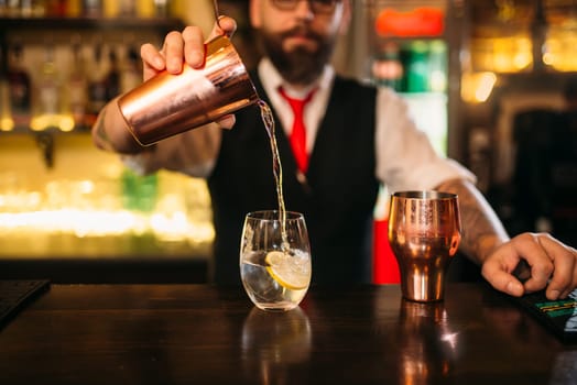 Bartender is making alcohol cocktail at bar counter. Barman with shaker