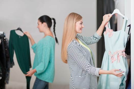 Two young women buyinng dresses in the shop